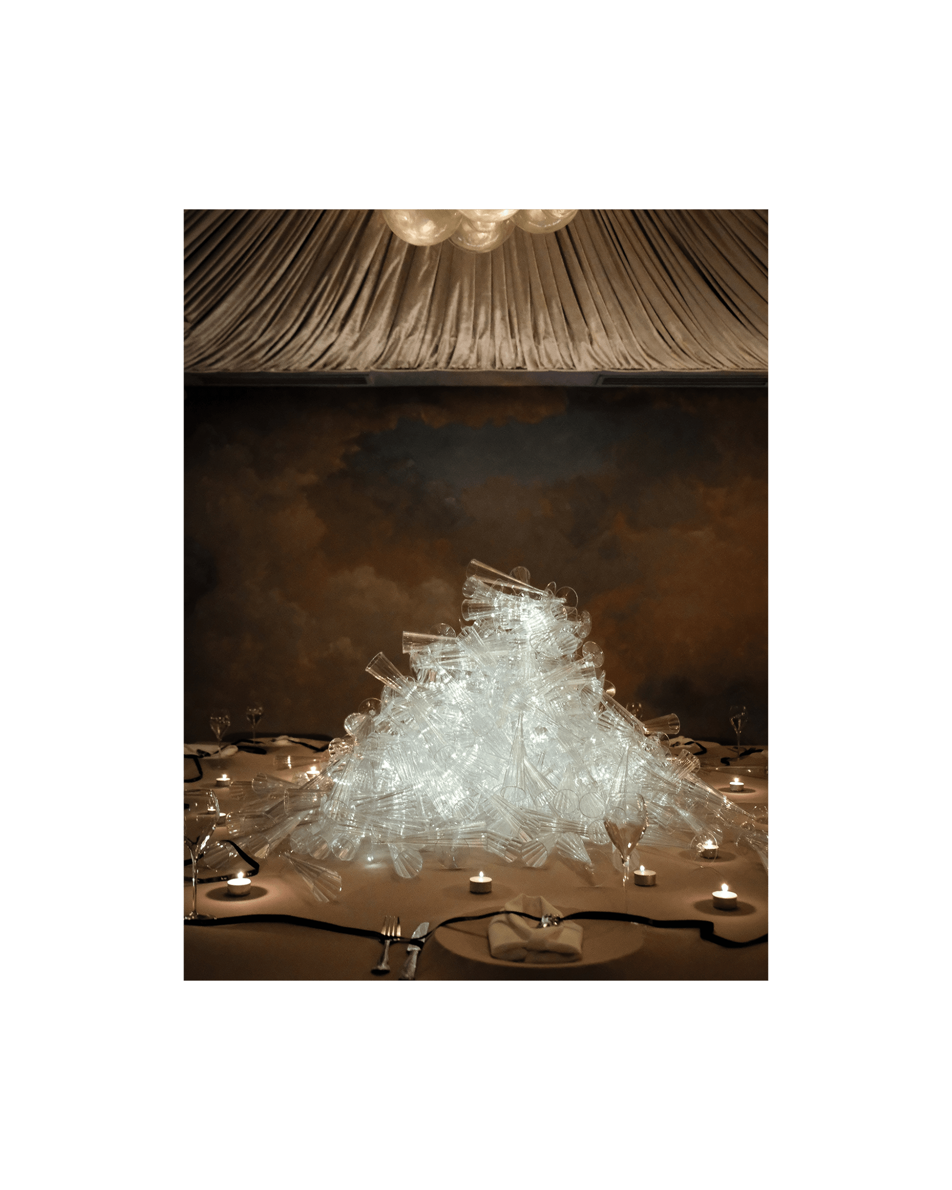 A pile of champagne glasses are lit from within, piled high in the middle of a dinner table