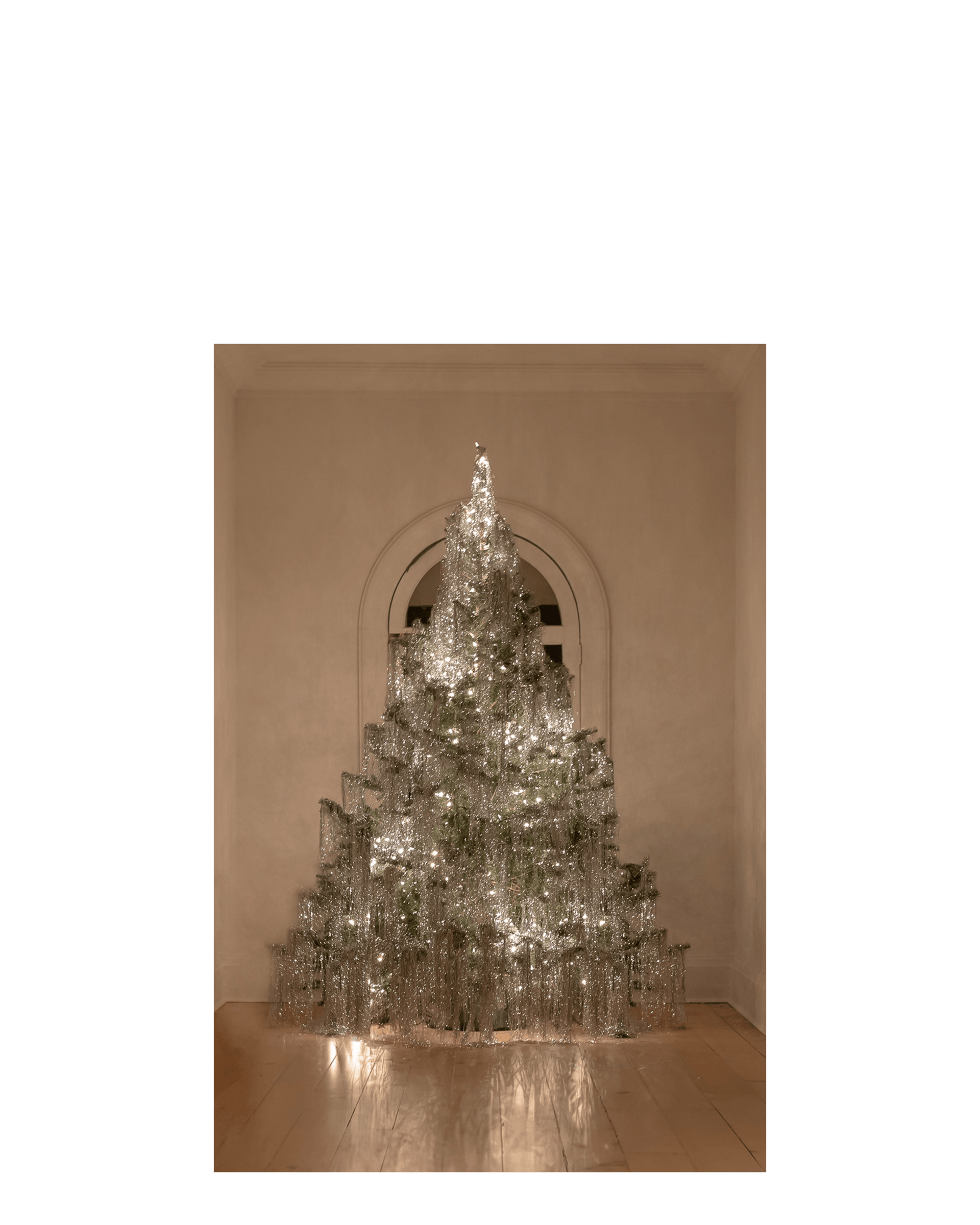 A christmas tree is adorned with silver tinsel and white lights