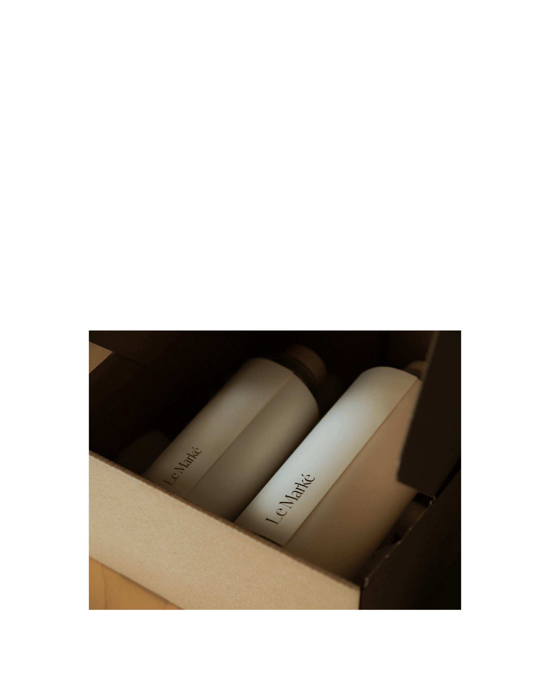 Two bottles of Le Marke olive oil are wrapped in a crisp branded paper
