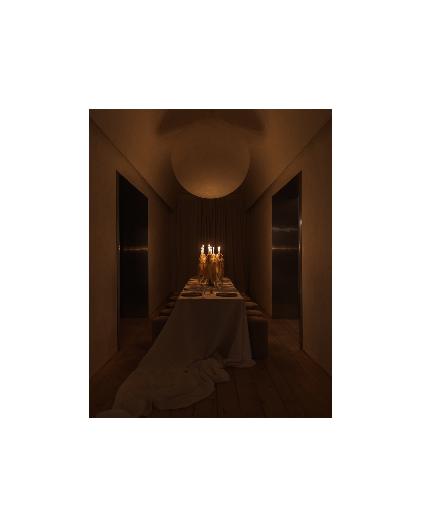 lit candelabra sits on a long table underneath large moon pendant, casting a warm glow