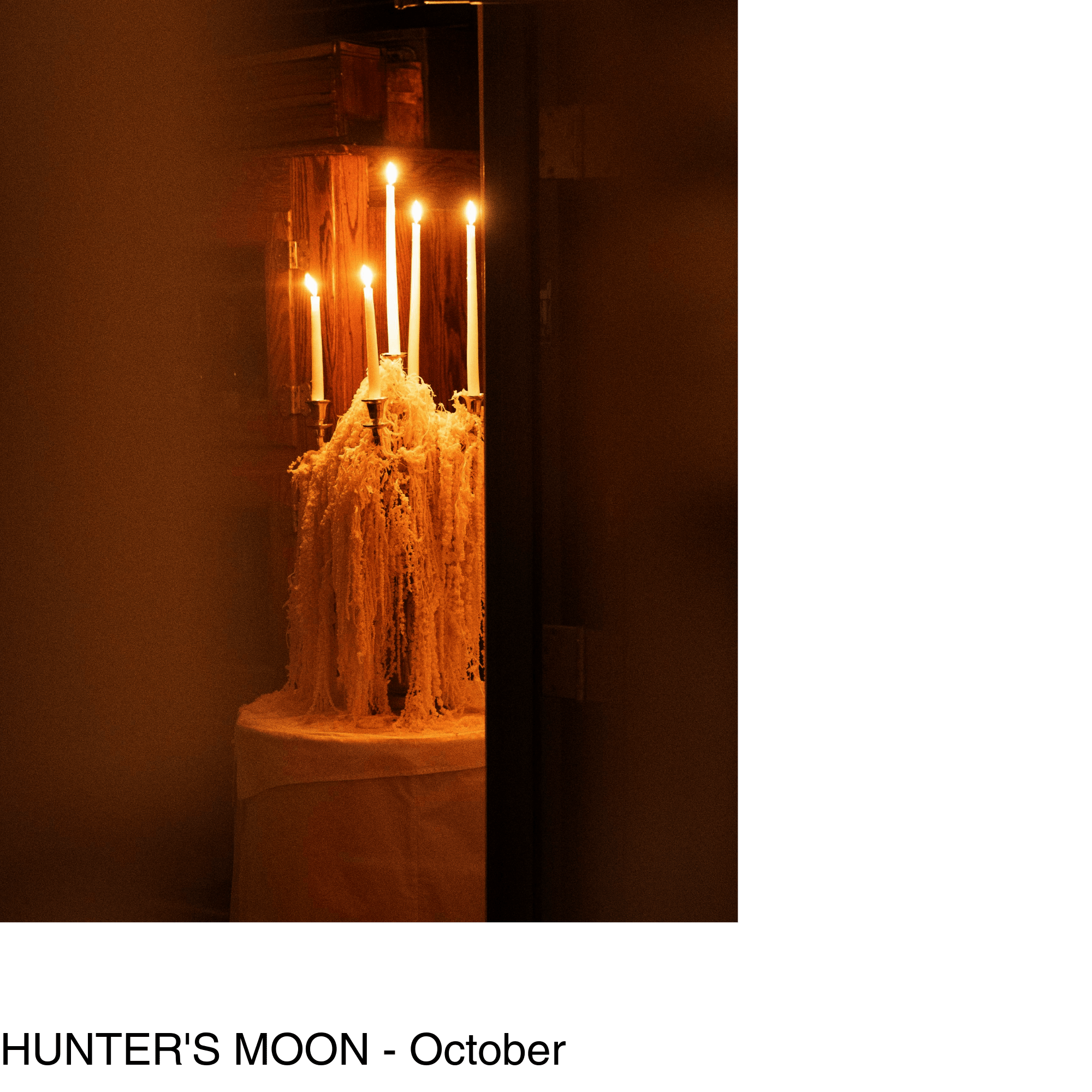 a lit candelabra sits on top of a table with a crisp white tablecloth. Hanging amaranthus flower cascades down the sides of the candelabra