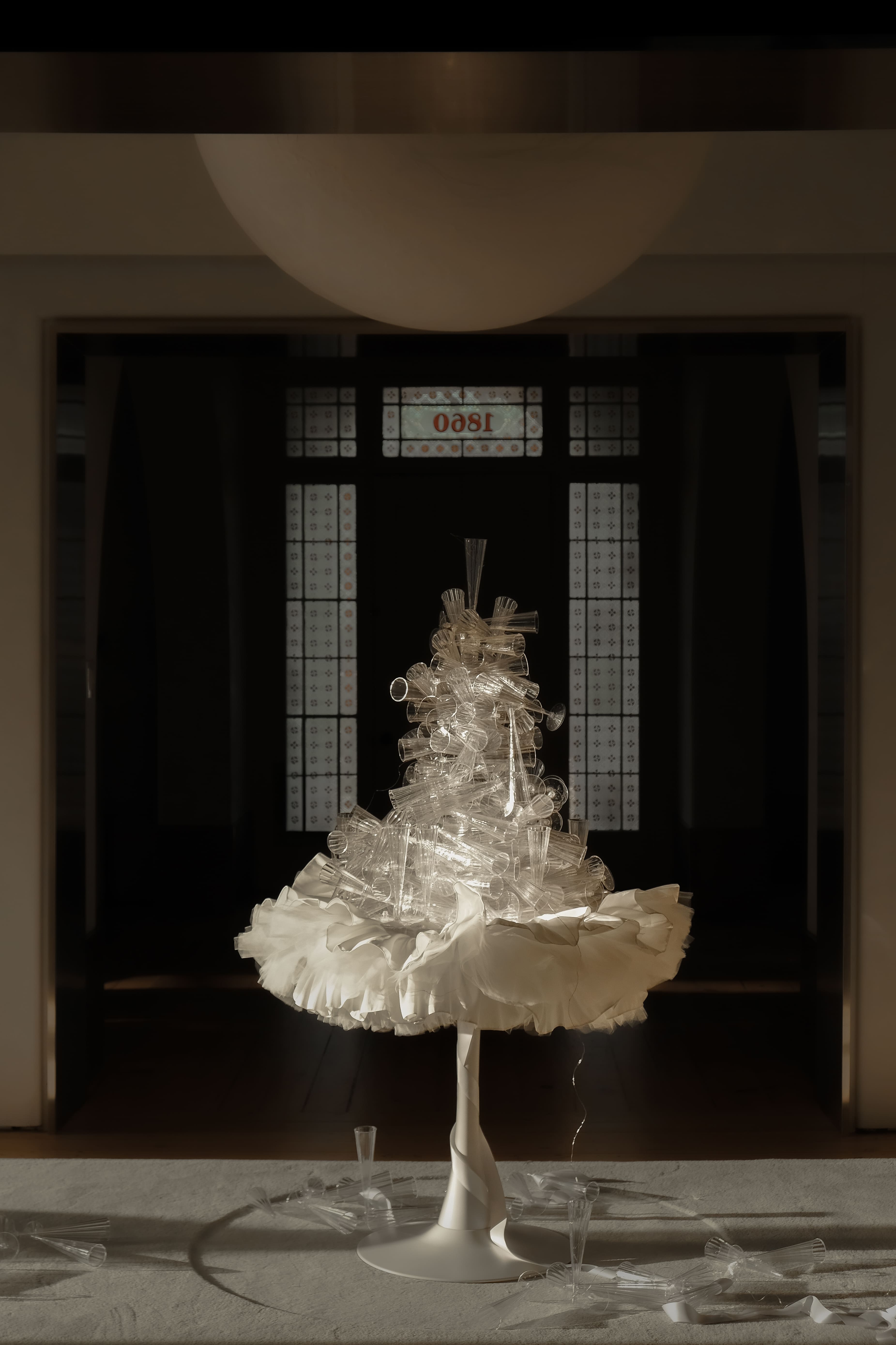 tower of champagne glasses piled on a white table with an ornate tulle tablecloth