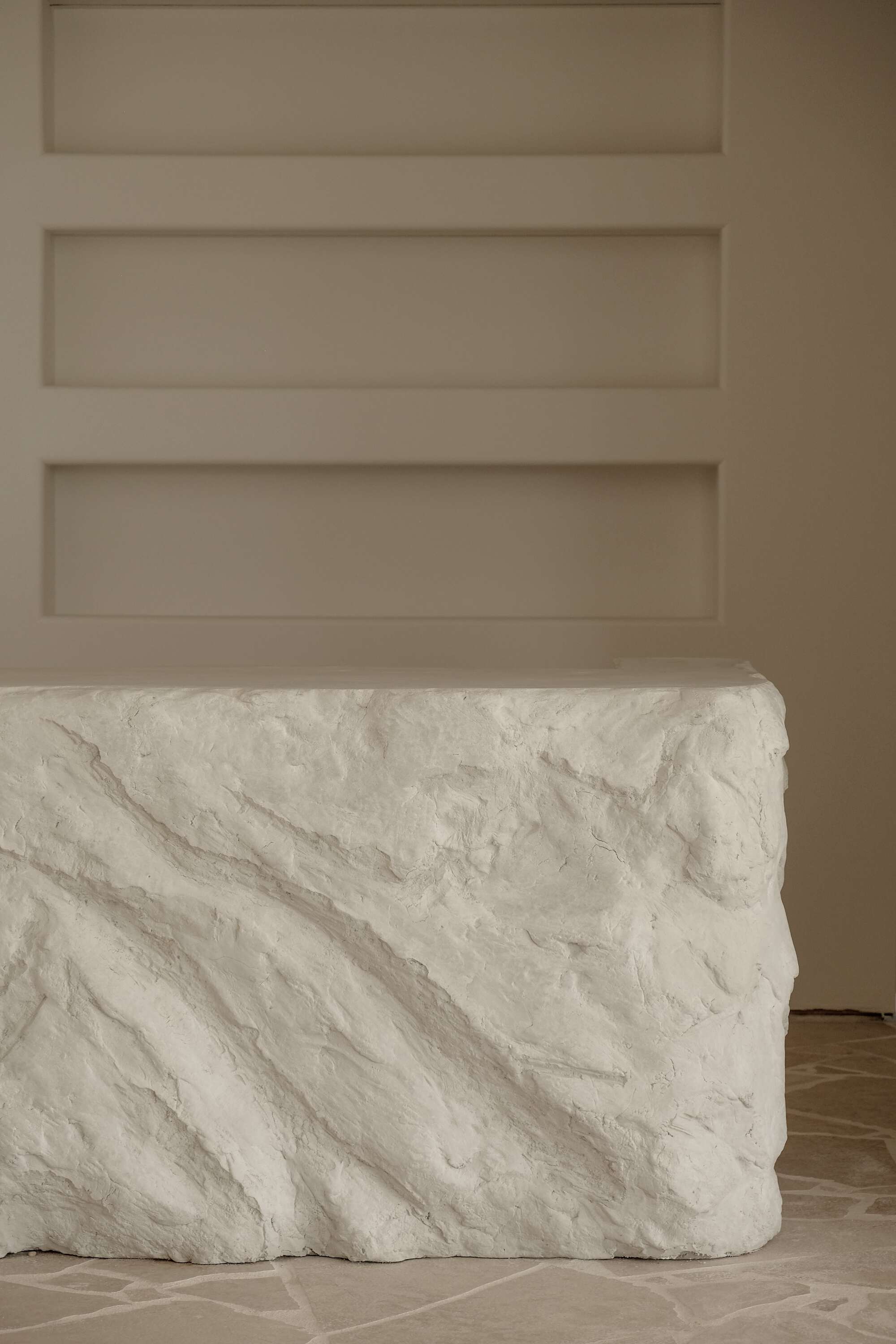 white textured stone bar with sunken shelves in the wall behind it