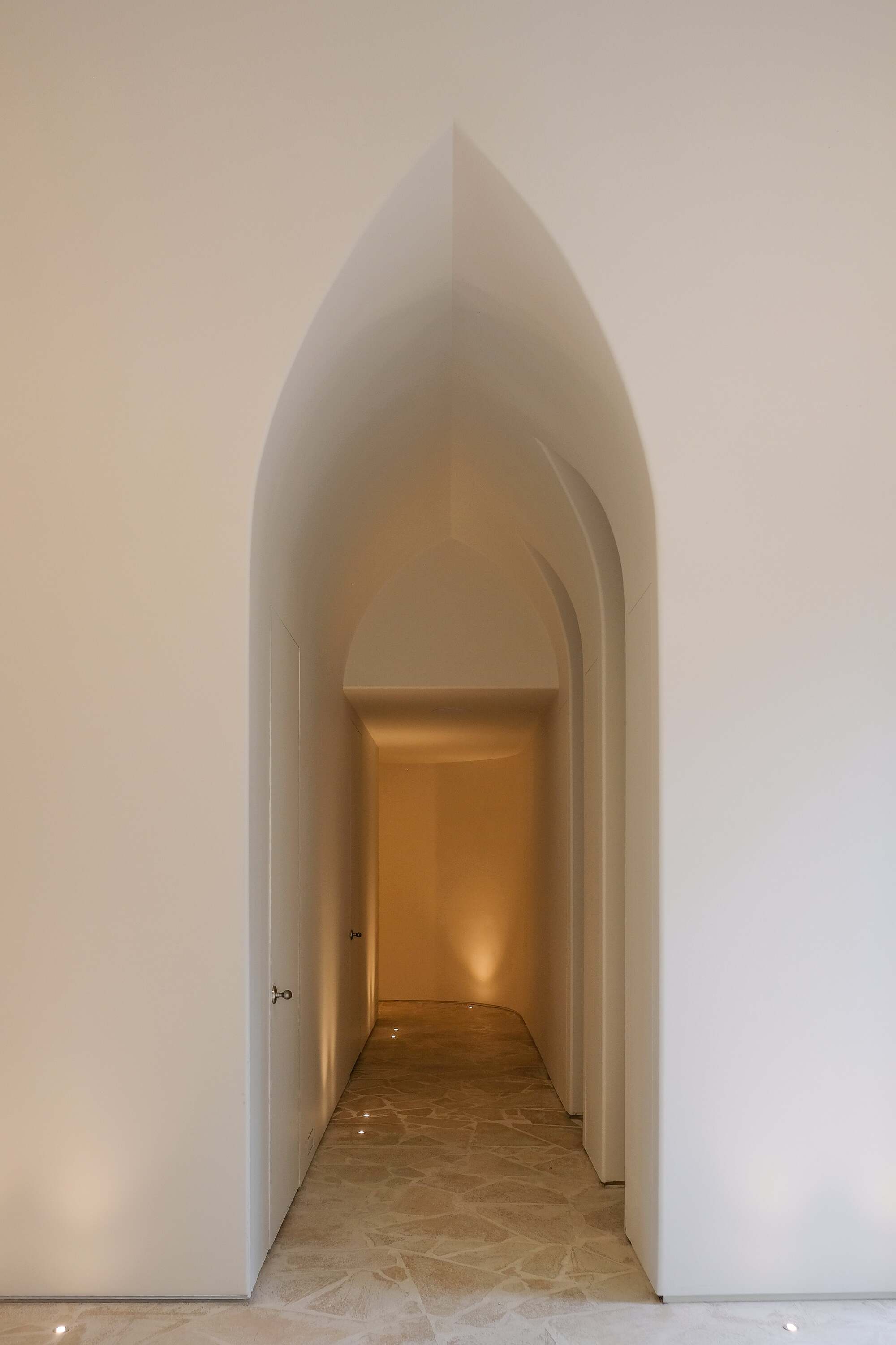 arched doorway reveals warmly lit hallway, flagstone floor 