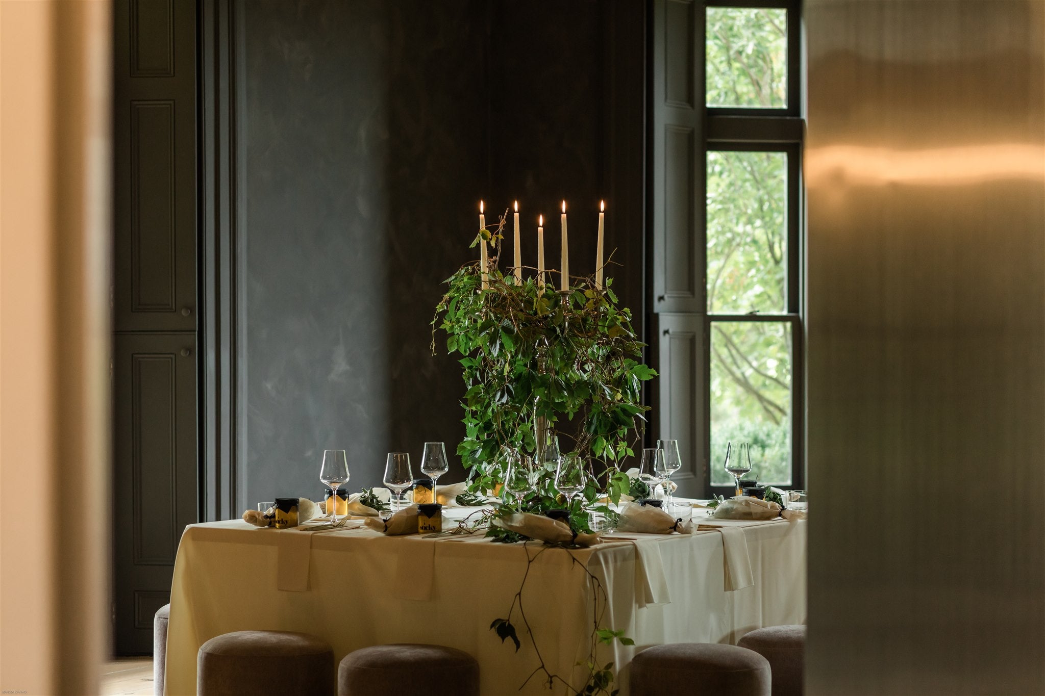 lit candelabra wrapped in vines sits in the middle of large square table