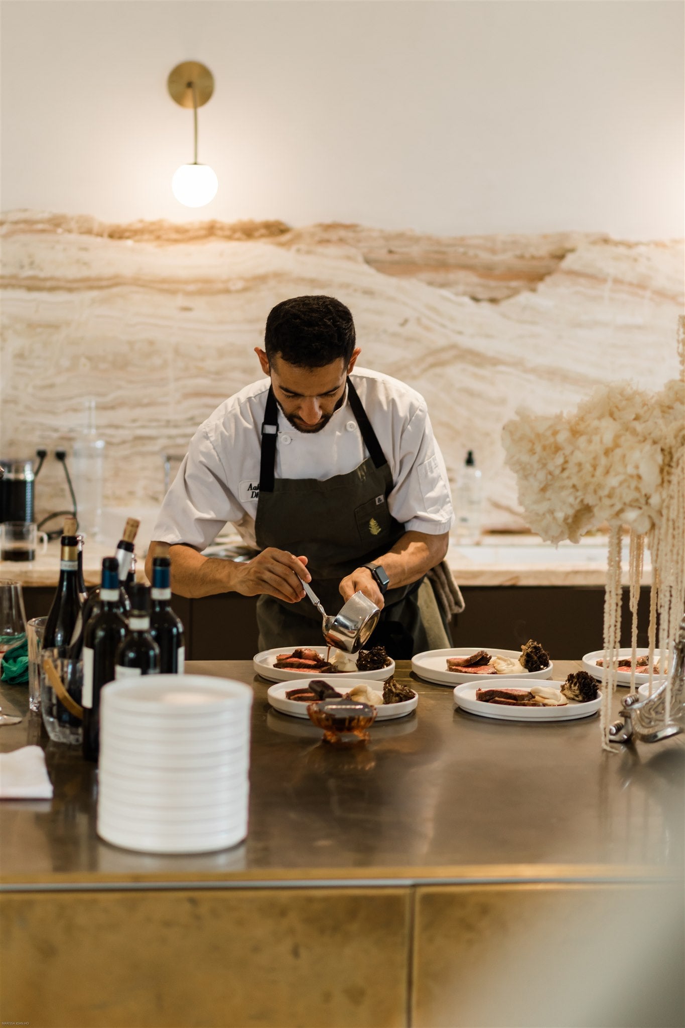 Chef Aakash Dhall adds sauce to a series of plates