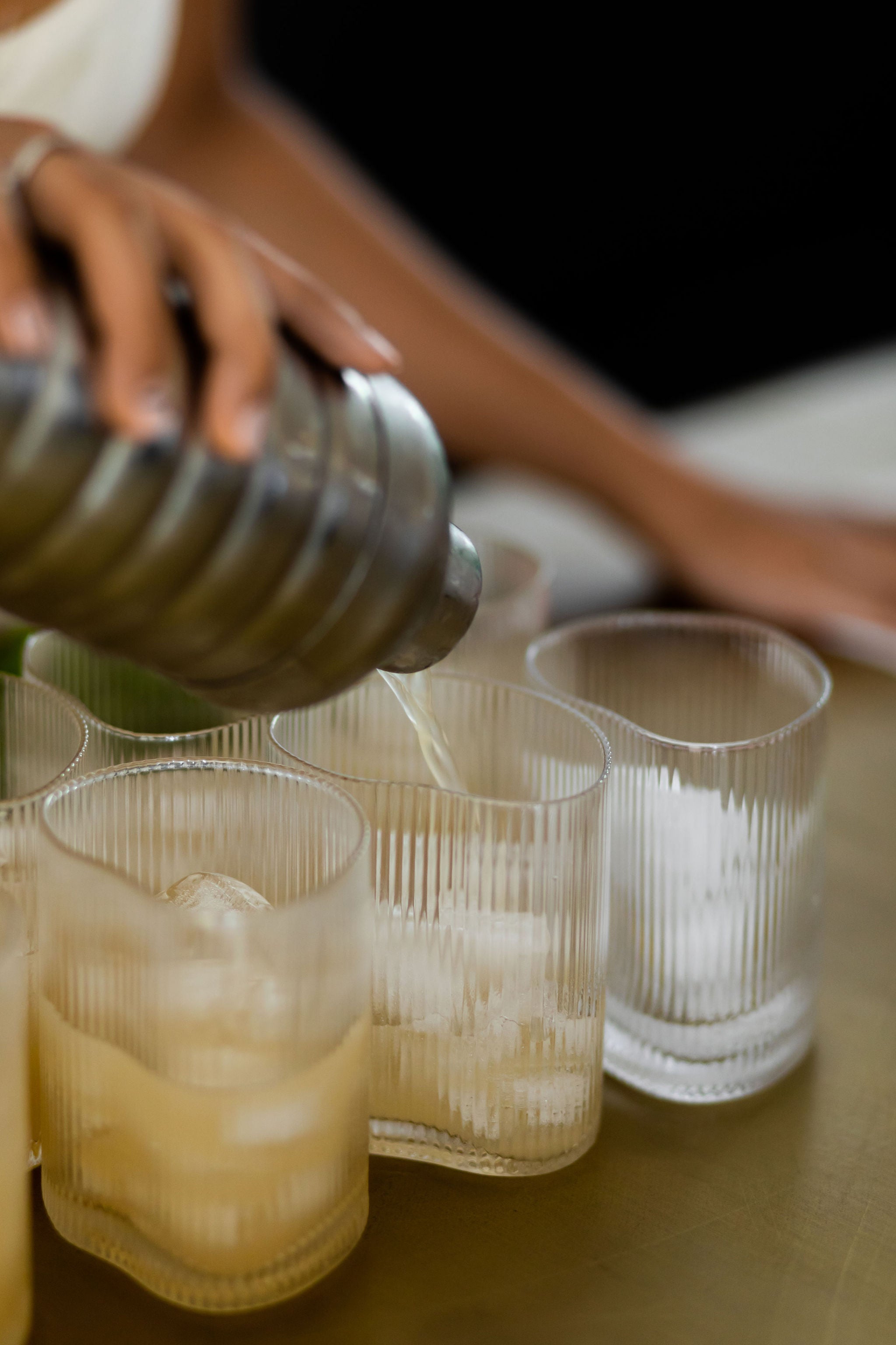 closeup of cocktail being poured into glasses