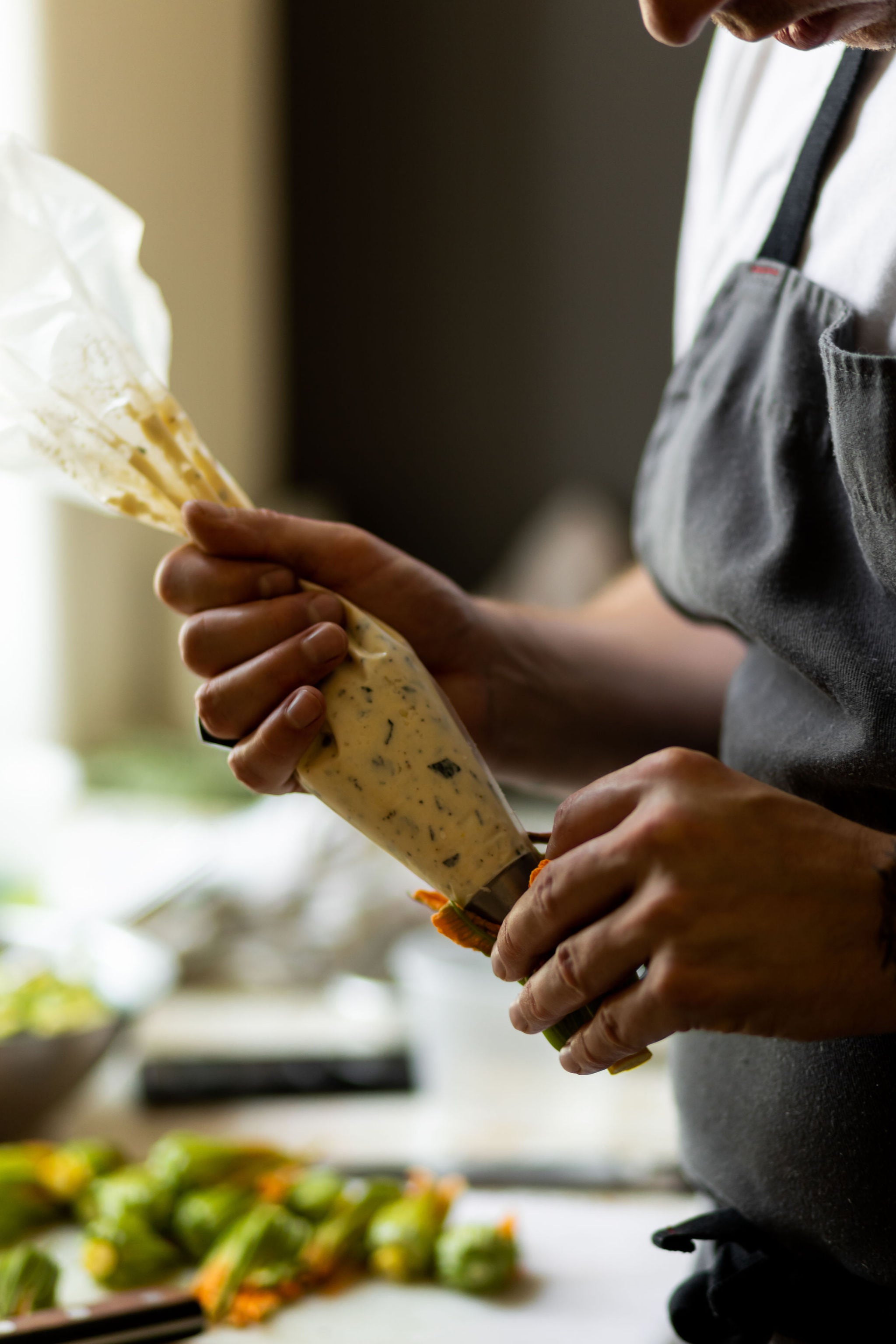 closeup of chef filling squash blossoms with piping bag