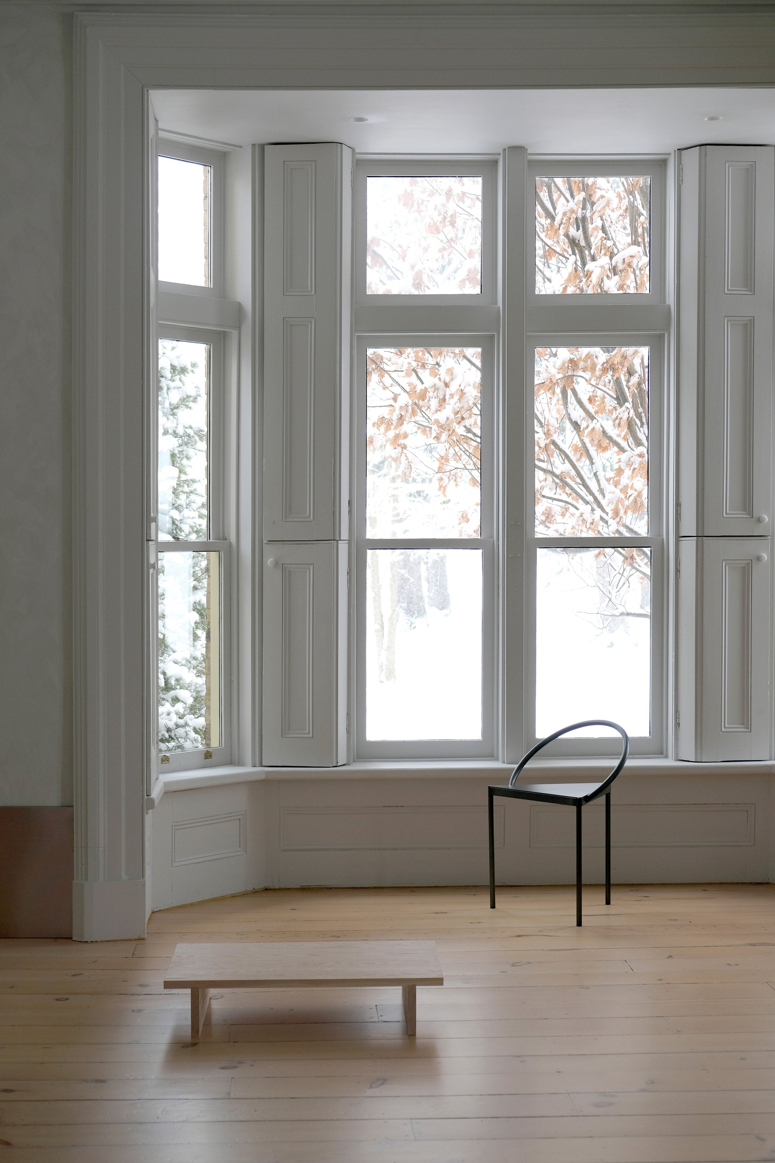 black steel chair with triangular base in front of large bay window