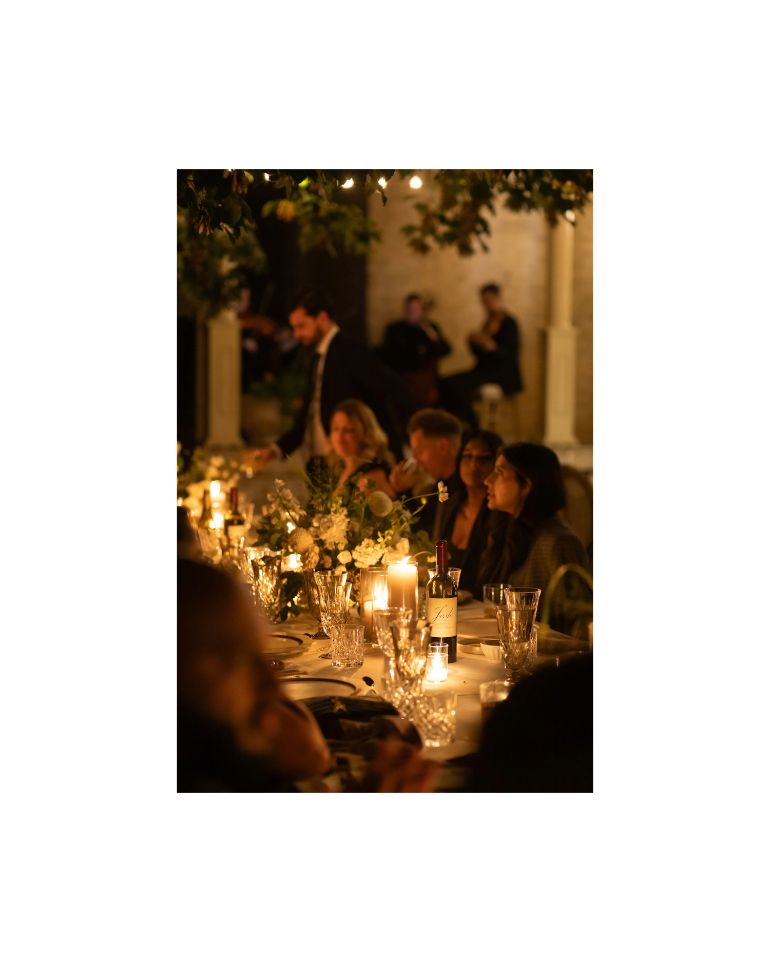 guests huddled around a candlelit table outside on the garden terrace
